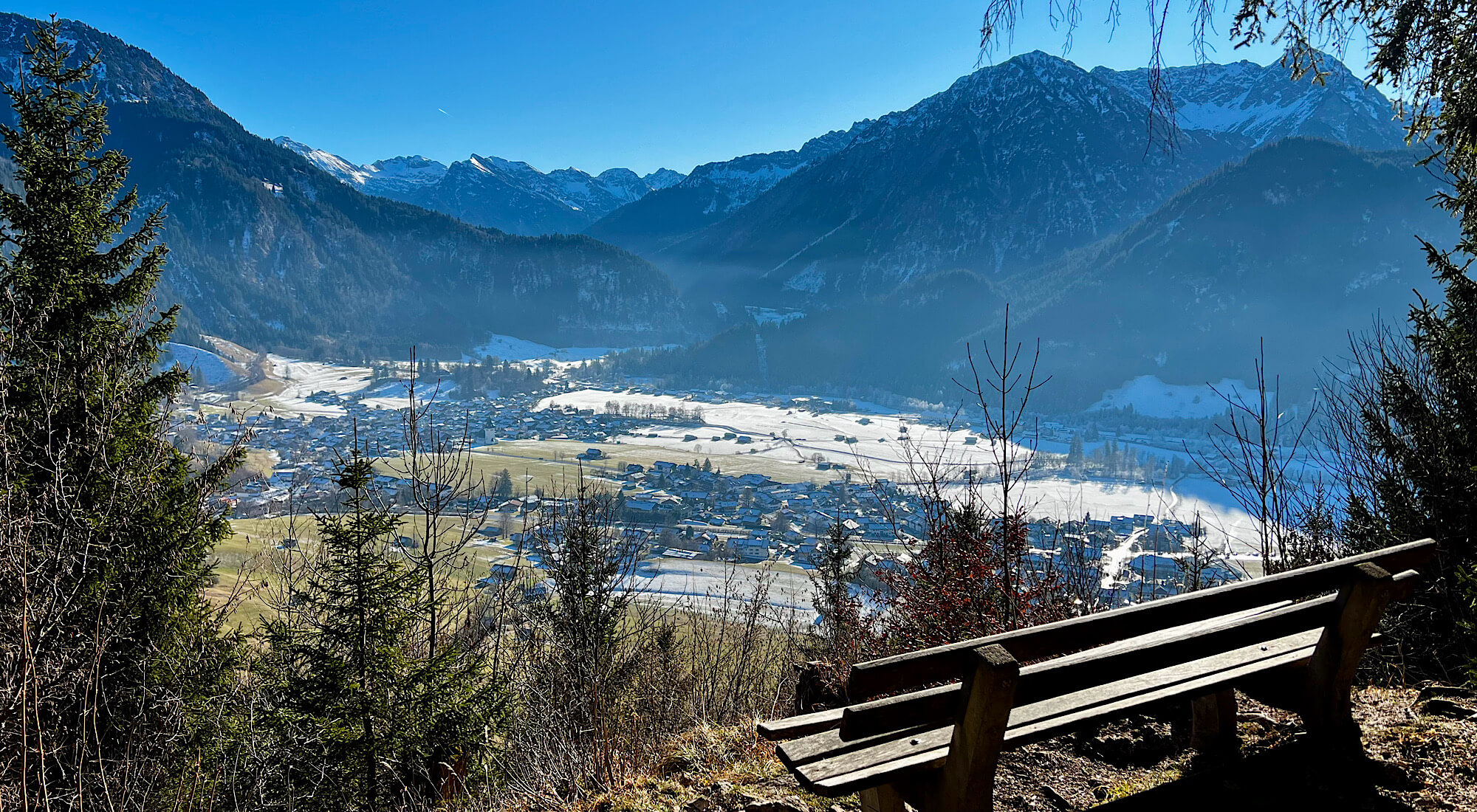 Blick ins noch teilweise verschneite Tal, bei Sonnenschein